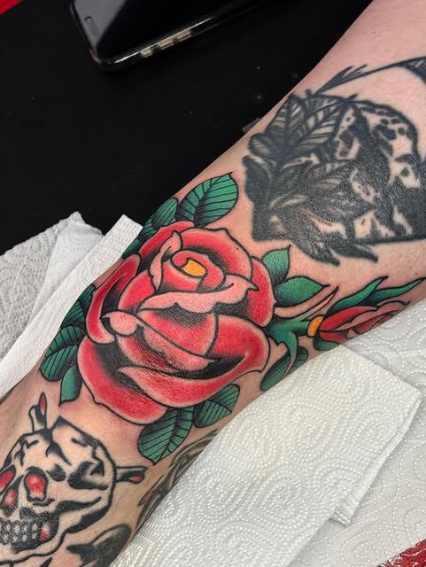 Traditional red rose tattoo with green leaves by Matt Pounder